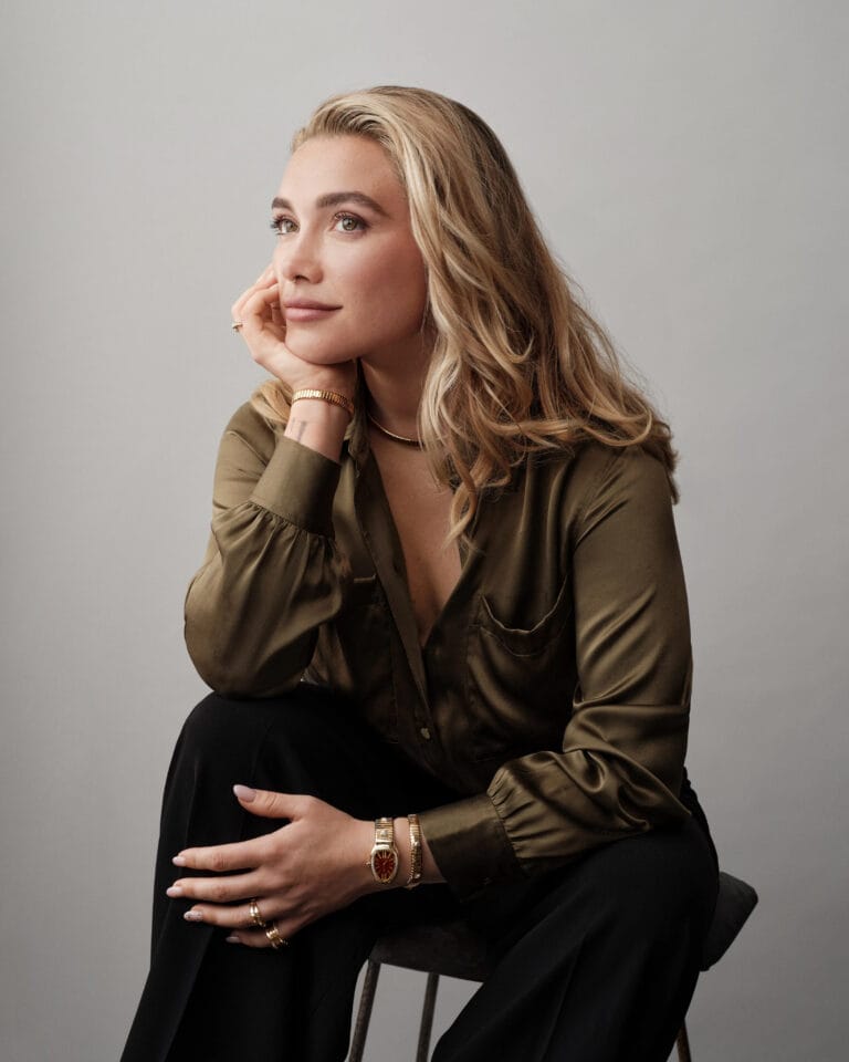Florence Pugh: Wears an olive green satin blouse with puffed sleeves, paired with black pants…