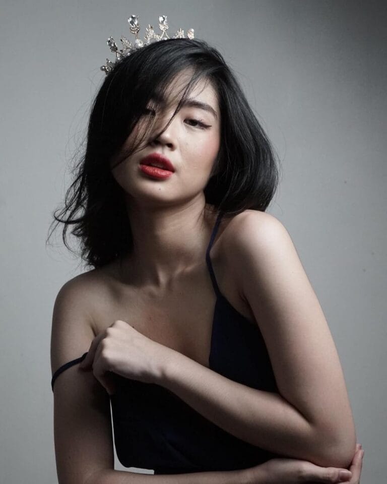 Azi Acosta: Wears a dark blue dress with thin straps, highlighting her elegant figure as she…