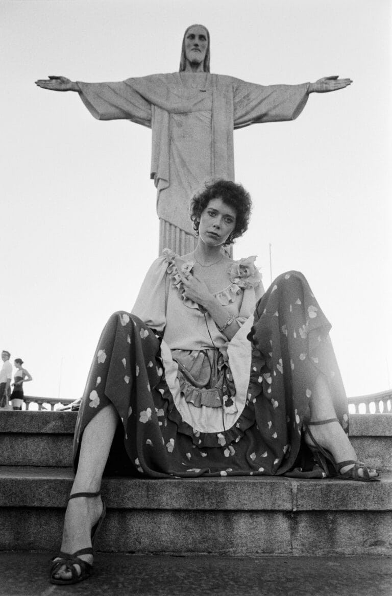 Sylvia Kristel: Poses on the stairs in a long floral print dress with ruffles, the…