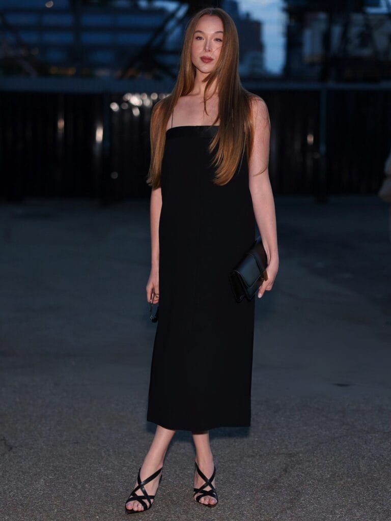 Ella Beatty: Luce un vestido negro sin mangas que cae hasta la mitad de la pantorrilla,…