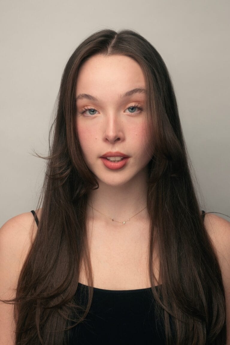 Ella Beatty: Wears a black blouse with thin straps that highlights her figure with an air…