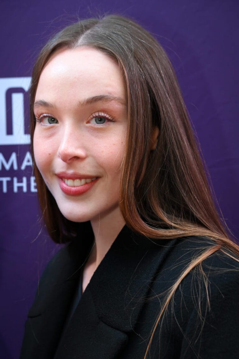 Ella Beatty: Wears a classic-cut black jacket with a sophisticated style that highlights her…