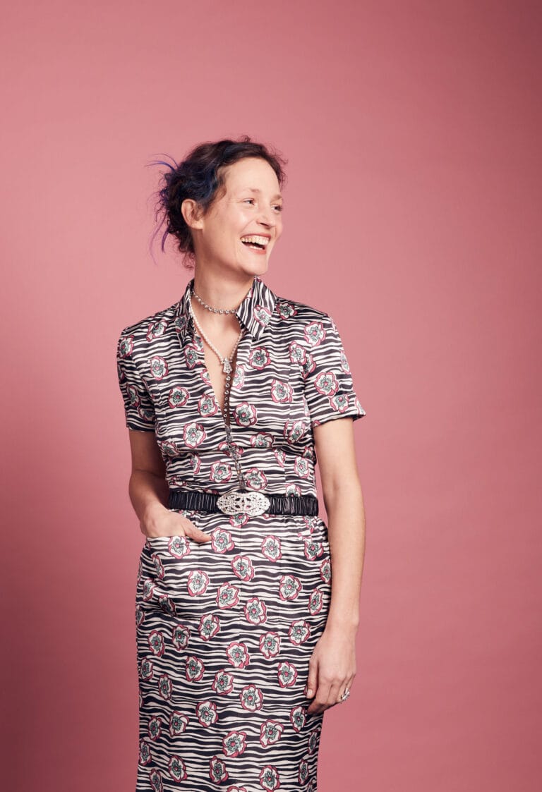 Vicky Krieps: Wears a midi dress with a striped and floral print in shades of…
