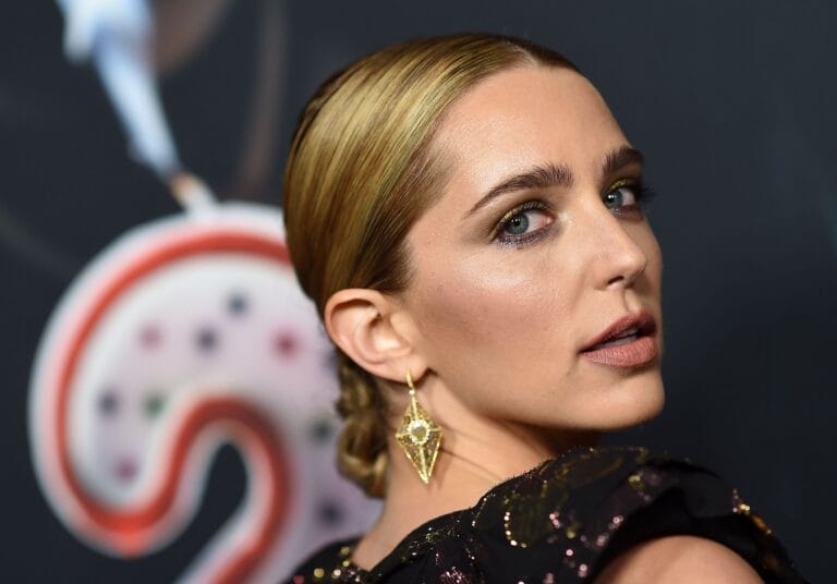 Jessica Rothe: Wears a black dress with sparkly details and a neckline that highlights her shoulders.…
