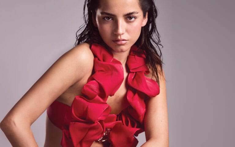 Isabela Merced: Wears a red top with dramatic ruffles that highlights her figure, creating a…