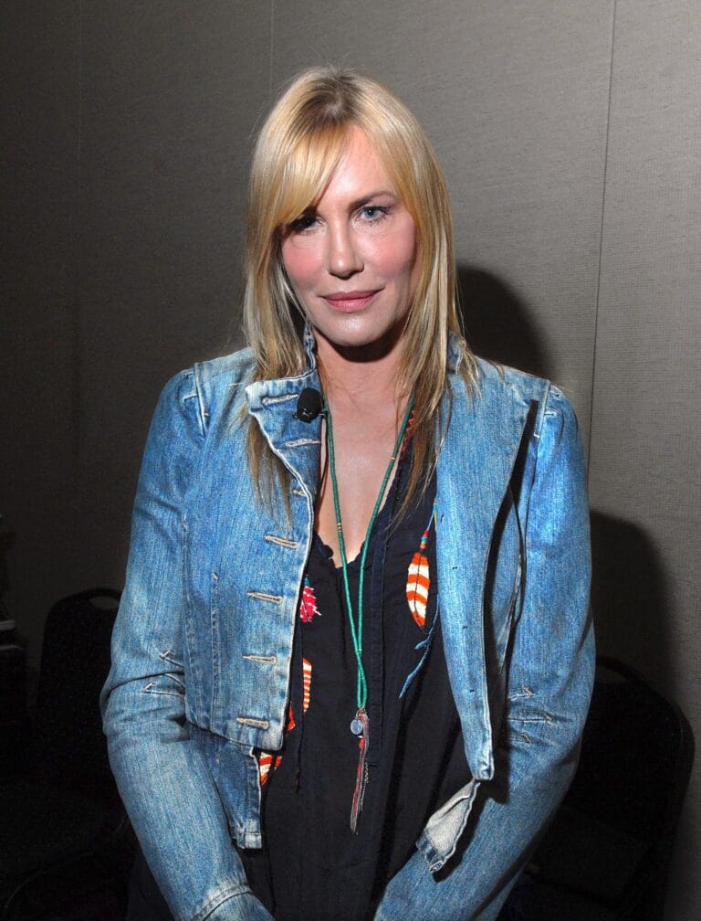 Daryl Hannah: Wears a denim jacket over a black blouse with colorful prints, creating a…
