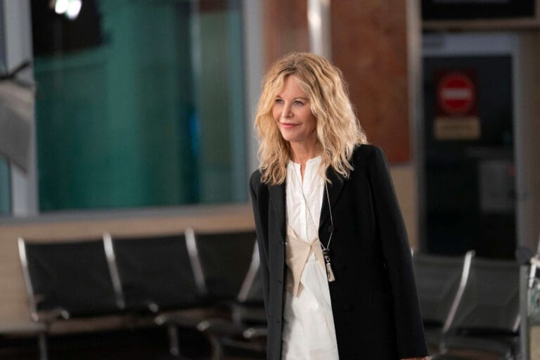 Meg Ryan: Wears an elegant black coat over a white blouse, with a distinctive necklace that…