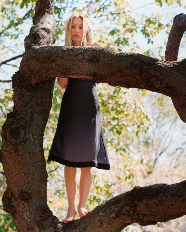 Piper Perabo: Standing barefoot on a sturdy tree branch, wearing a dress…