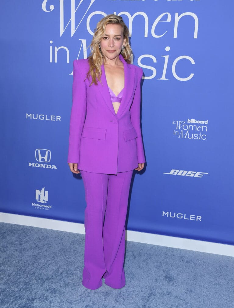 Piper Perabo: Wears a tailored suit in a vibrant purple tone, with a modern-cut jacket…