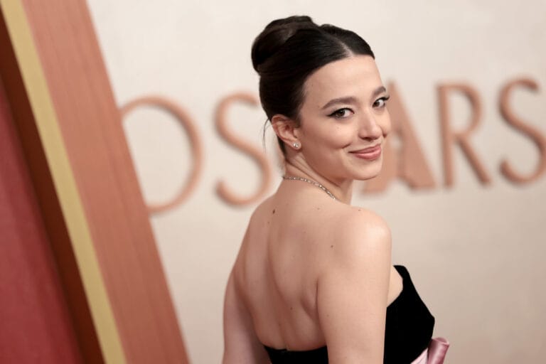 Mikey Madison: Wears an elegant sleeveless black dress that highlights her figure, with a detail…