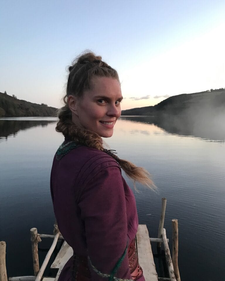 Ragga Ragnars: Posa de pie en un embarcadero, mirando hacia atrás con una sonrisa serena, mientras…