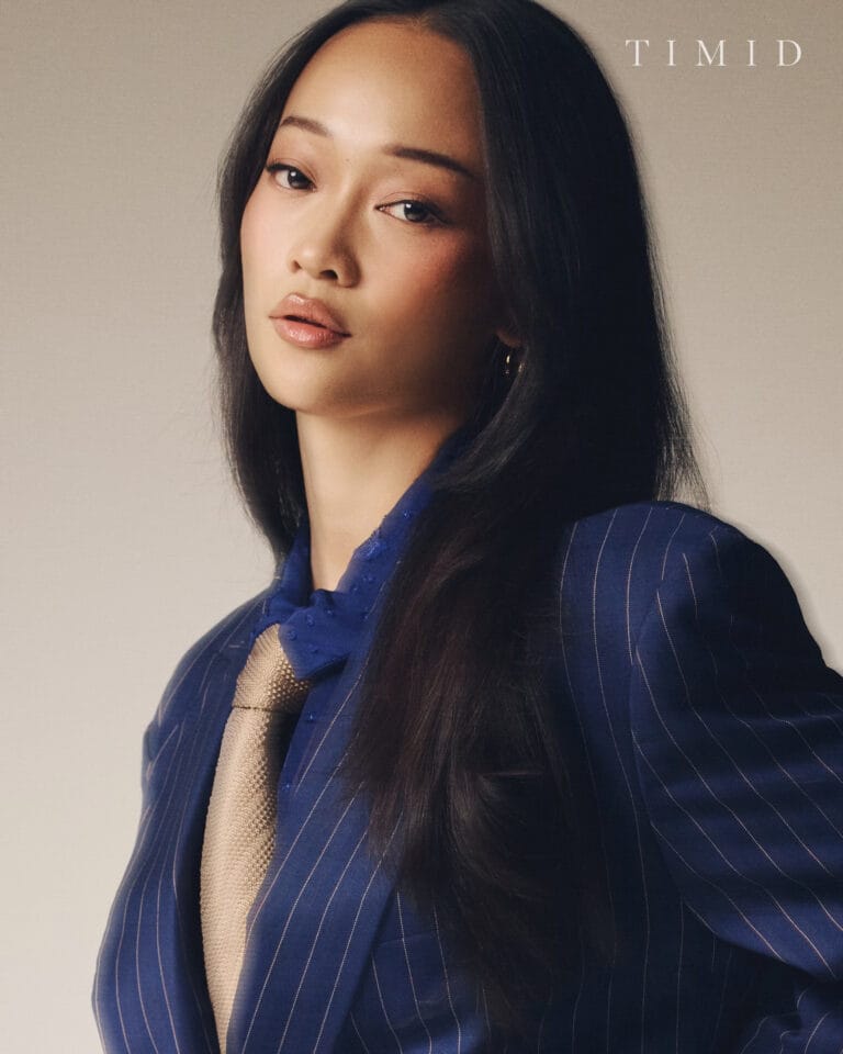 Callina Liang: Wears a blue pinstripe suit, complemented by a gold tie that adds…