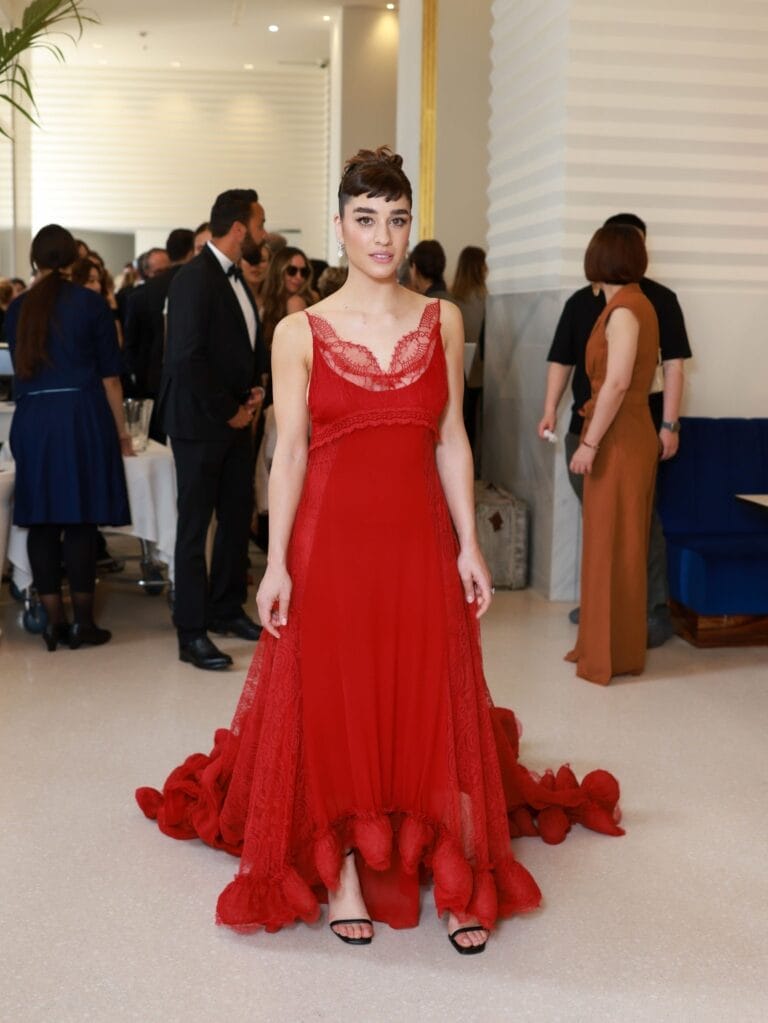 Simona Tabasco: Wearing a stunning red dress with lace details and a cascading skirt that…