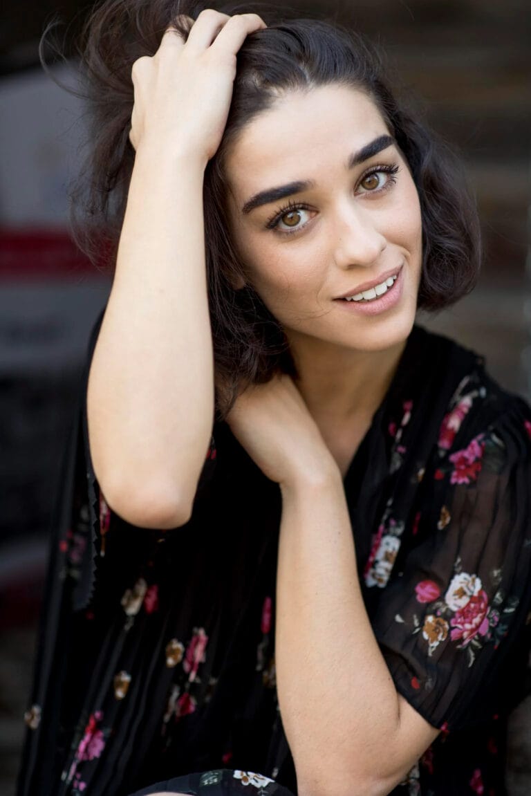 Simona Tabasco: Wears a black floral-print kimono, sitting cross-legged with a…