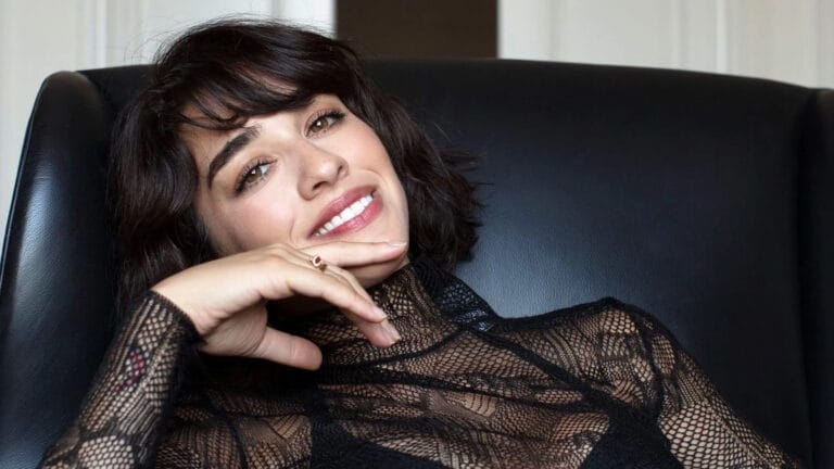 Simona Tabasco: Wears a black lace blouse with a sophisticated style, while leaning back…