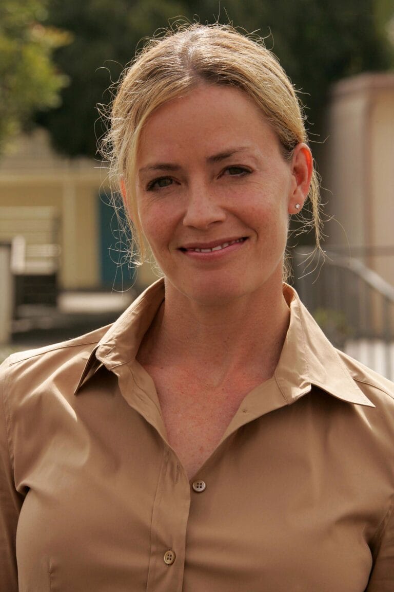Elisabeth Shue: Wearing a beige silk blouse with a classic cut and visible buttons, which…