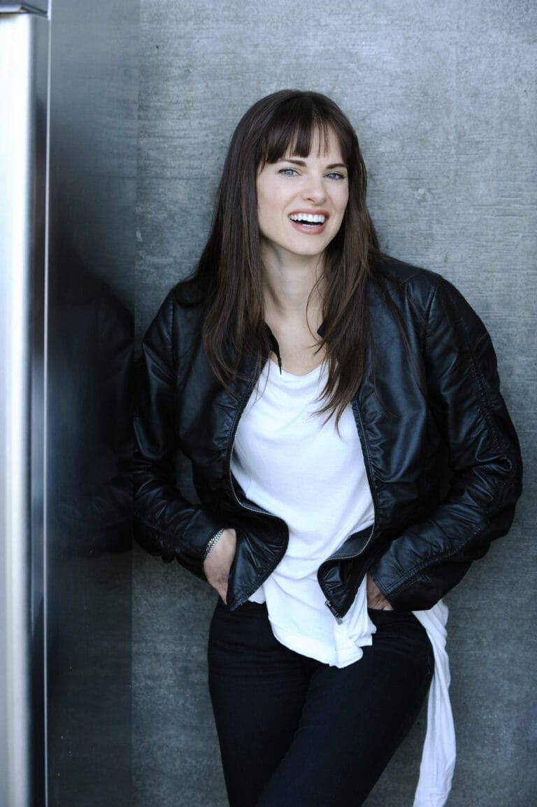 Amy Bailey: Luce una chaqueta de cuero negra sobre una camiseta blanca, con jeans oscuros ajustados…