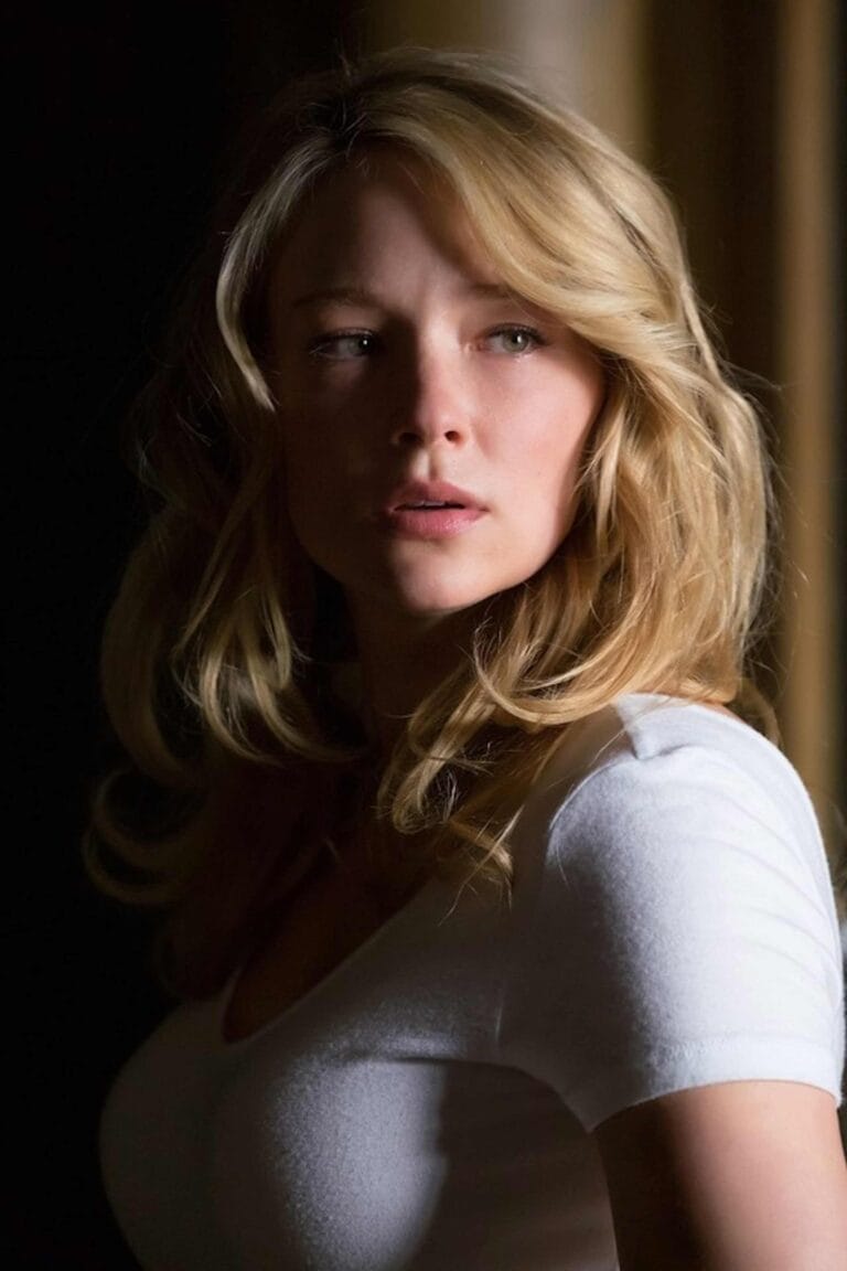 Haley Bennett: Luce una camiseta blanca ajustada que resalta su figura, con un fondo de sombras…