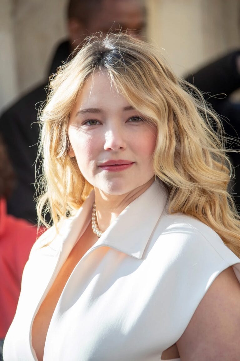 Haley Bennett: Luce un vestido blanco con un escote pronunciado y un diseño minimalista, complementado con…