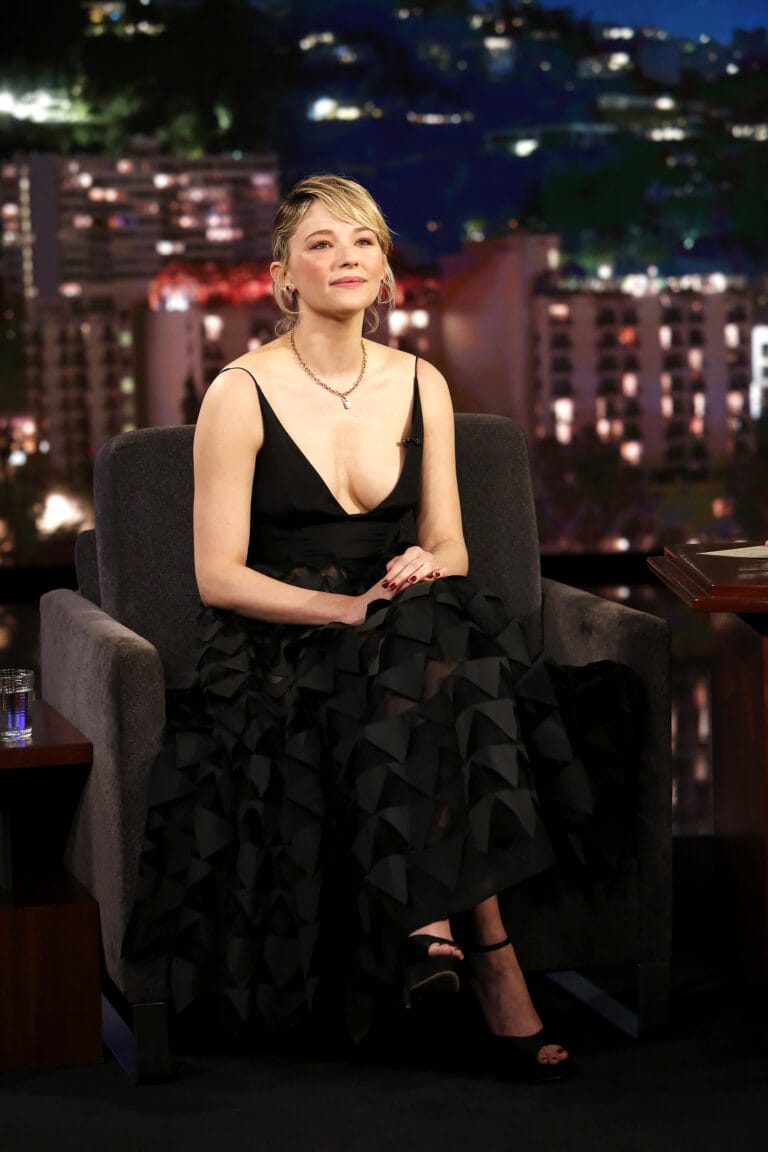 Haley Bennett: Luce un vestido negro de corte profundo y detalles texturizados, sentado en un sillón…