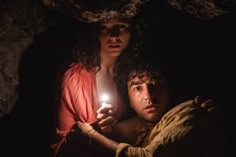 Thomasin McKenzie: Aparece en un entorno oscuro y cavernoso, aferrándose a una vela que emite una…