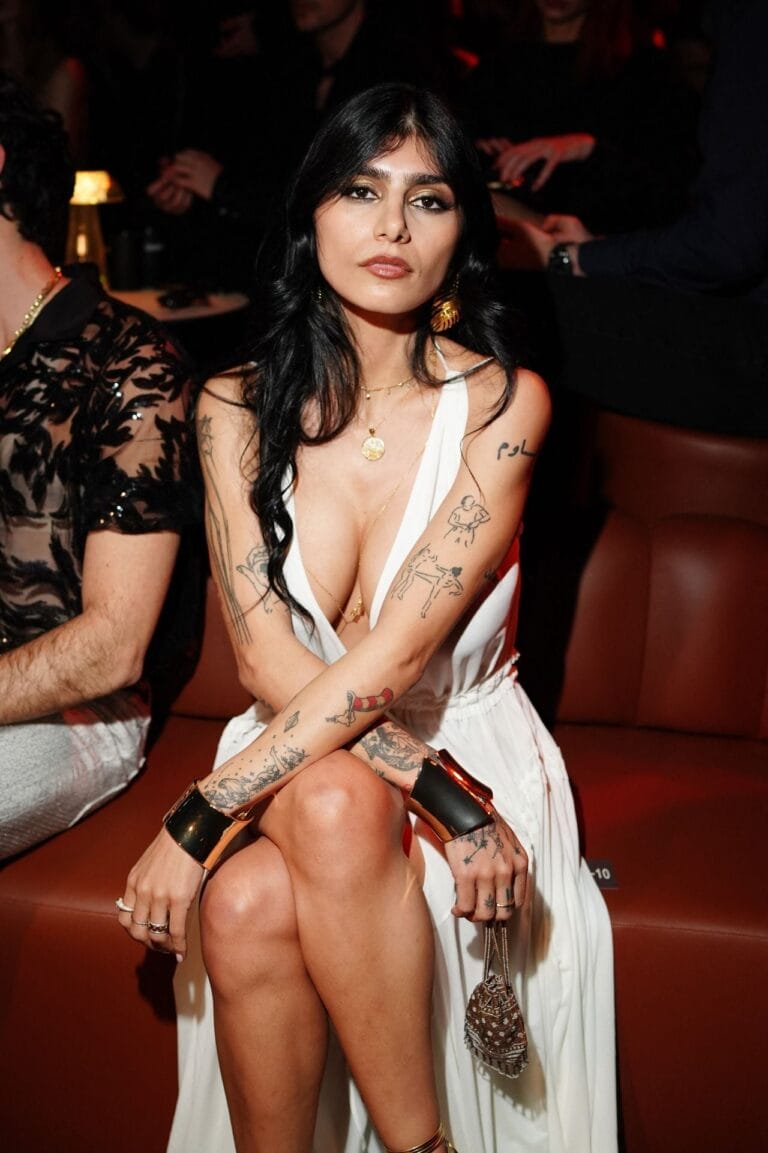 Mia Khalifa: Luce un vestido blanco con un escote profundo, sentada con las piernas cruzadas en…