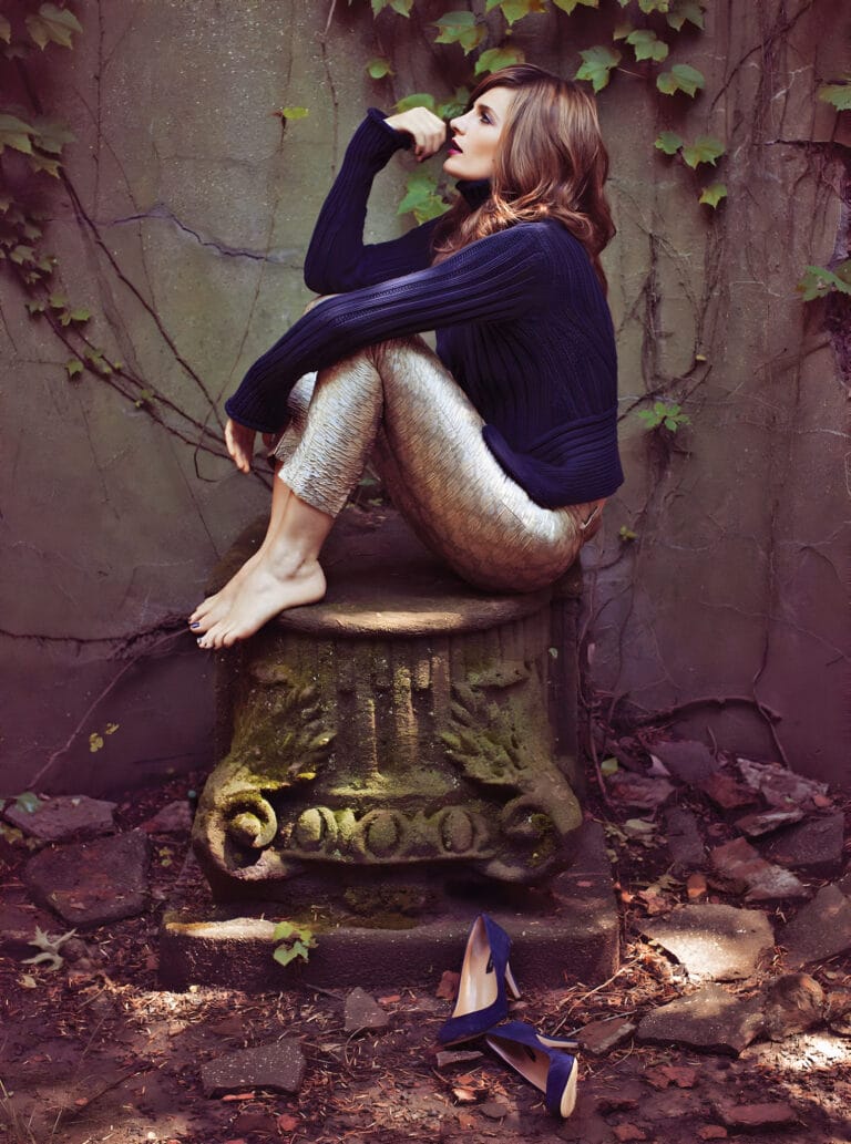 Stana Katić: Está sentada sobre un pedestal de piedra, con las piernas flexionadas y los pies…