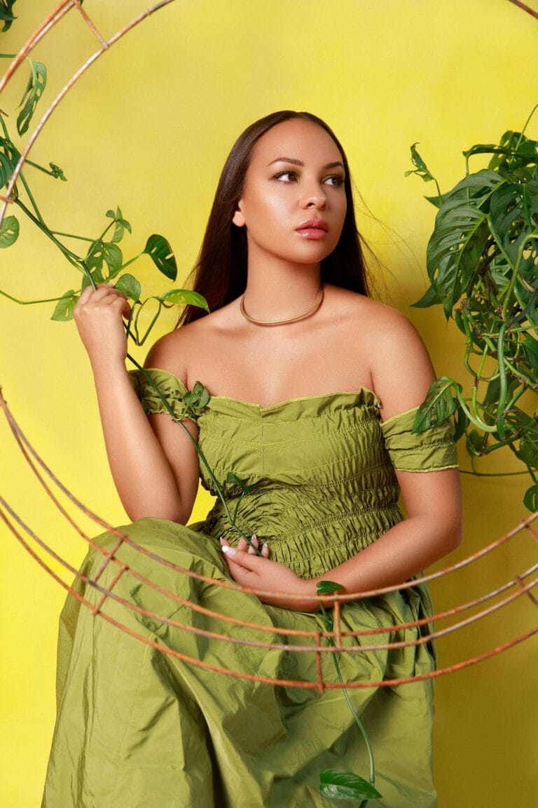 Jasmine Cephas Jones: Luce un vestido verde oliva con detalles fruncidos y escote recto, mientras se apoya…