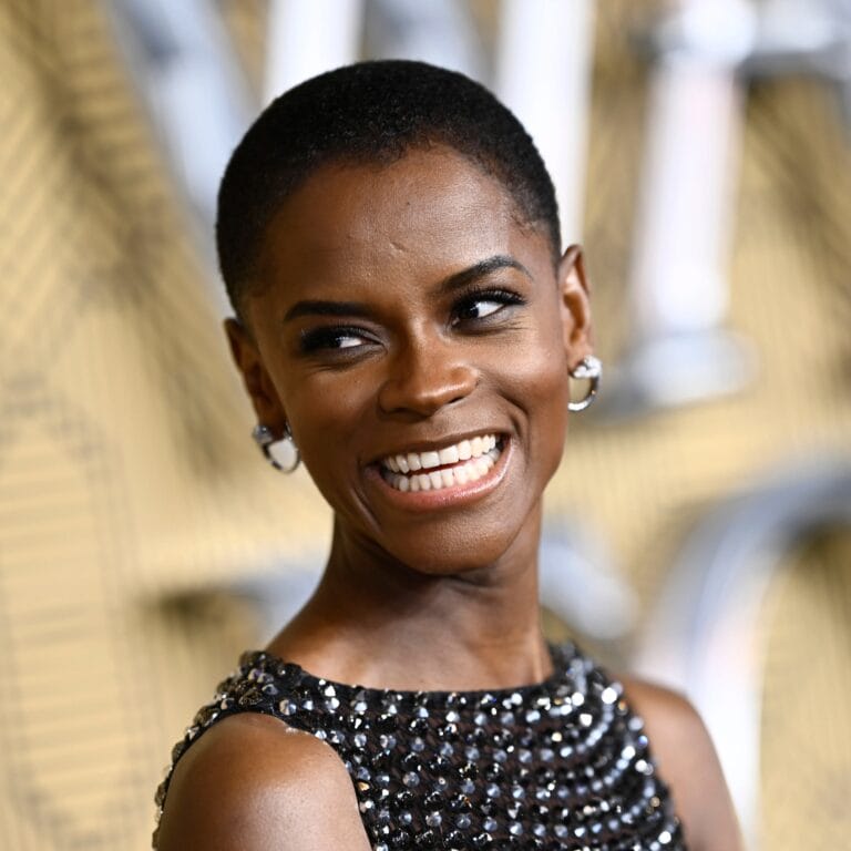 Letitia Wright: Luce un vestido negro con detalles brillantes que destacan su elegancia, sonriendo con confianza.…