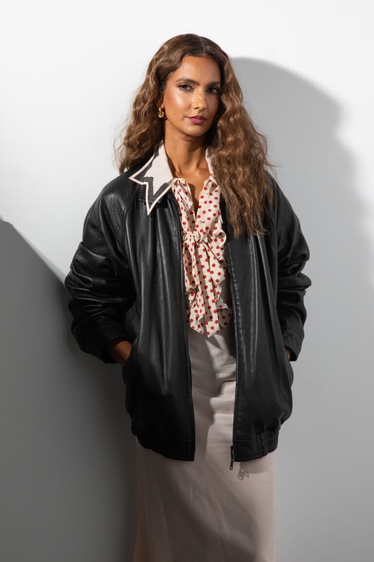 Poorna Jagannathan: Luce una blusa blanca con lunares rojos, adornada con un lazo en el cuello,…