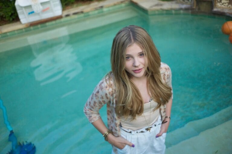 Chloë Grace Moretz: Wears a black camisole under a light jacket with a floral print,…