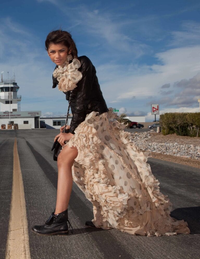 Zendaya: Wears a long beige chiffon dress with ruffles and a polka-dot print that…