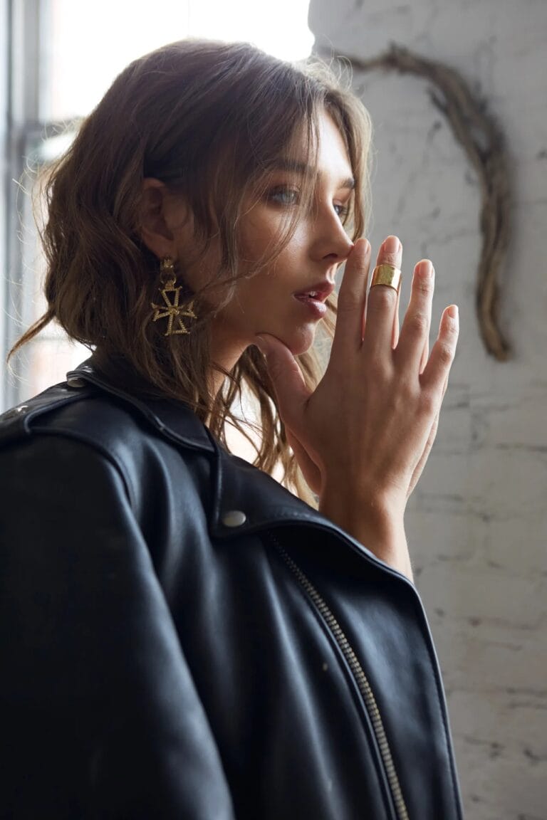 Rachel Cook: Wears a black leather jacket with metallic details, while gently leaning the…