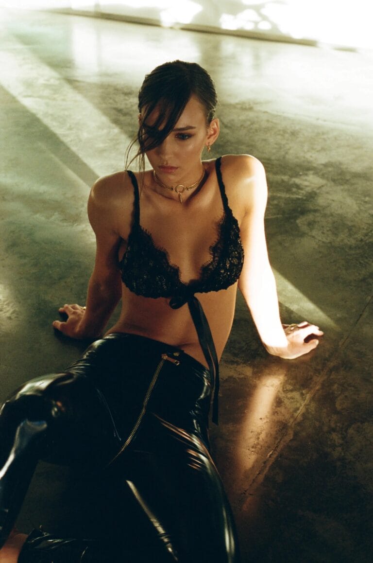Rachel Cook: Poses on the floor, wearing a black lace top that reveals…