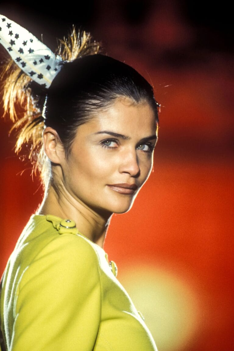 Helena Christensen: Wears a vibrant yellow sweater with shoulder details, paired with a scarf…
